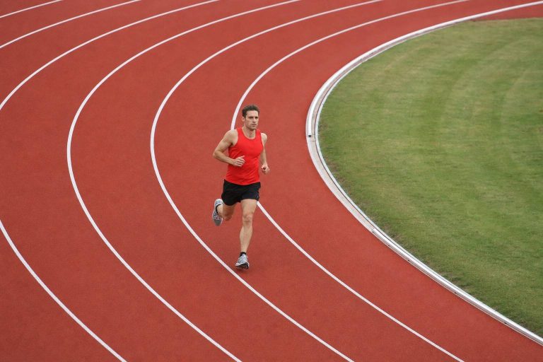 A runner holding an even, controlled pace around the bend of an outdoor running track
