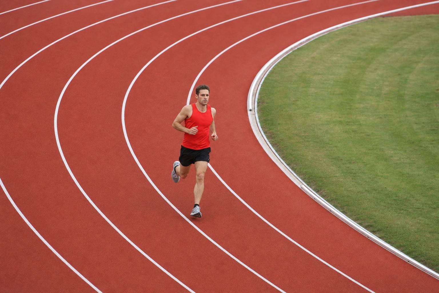 A runner holding an even, controlled pace around the bend of an outdoor running track