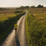 A runner on an empty country lane that stretches away into the distance
