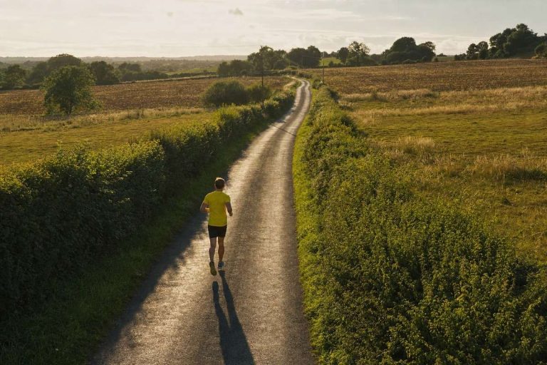 A runner on an empty country lane that stretches away into the distance