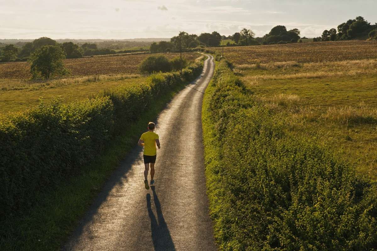 A runner on an empty country lane that stretches away into the distance